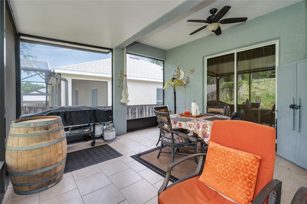 A screened-in patio features tile flooring, a dining set, a grill, and an orange chair — 2474 CIMMARON ASH WAY, APOPKA, FL