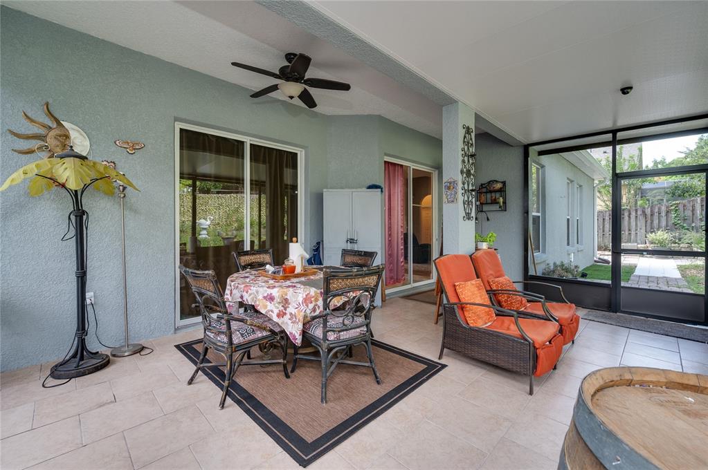 A covered patio features tile flooring, a dining set, lounge chairs, and a screened enclosure — 2474 CIMMARON ASH WAY, APOPKA, FL