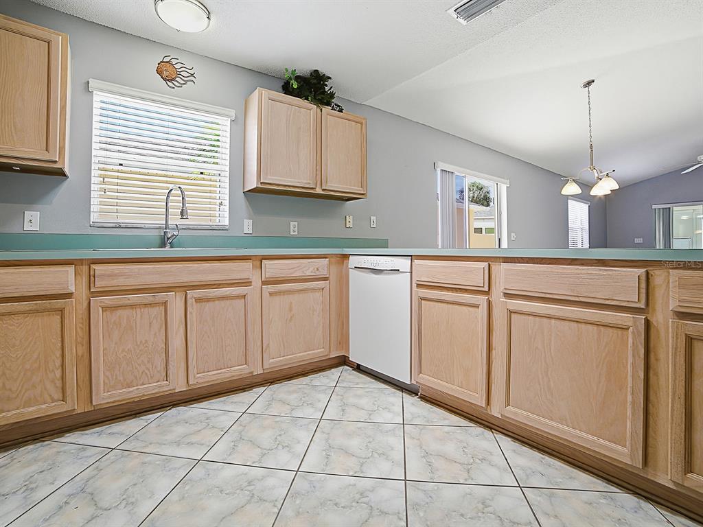 A kitchen features light wood cabinets, a white dishwasher, and light-colored tiled flooring — 872 WINCHESTER COURT, THE VILLAGES, FL