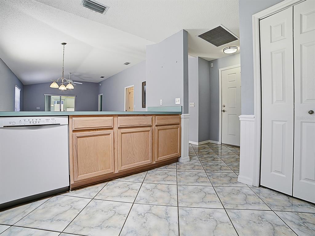 A kitchen with light wood cabinets, a white dishwasher, and marble-patterned tile flooring — 872 WINCHESTER COURT, THE VILLAGES, FL