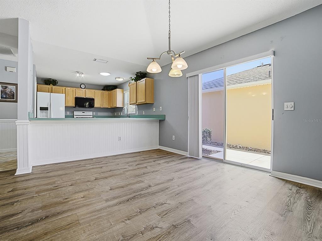 A kitchen with light wood cabinets and a breakfast bar opens to a dining area — 872 WINCHESTER COURT, THE VILLAGES, FL