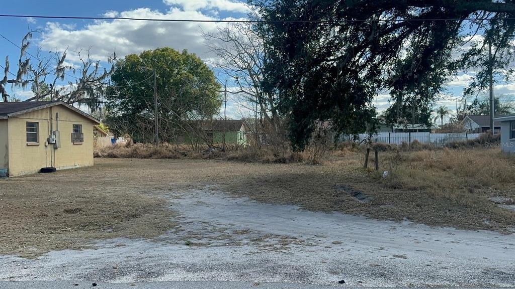 A vacant, grassy lot sits next to a small, yellow single-story house — 642 PETERSON STREET, WAUCHULA, FL