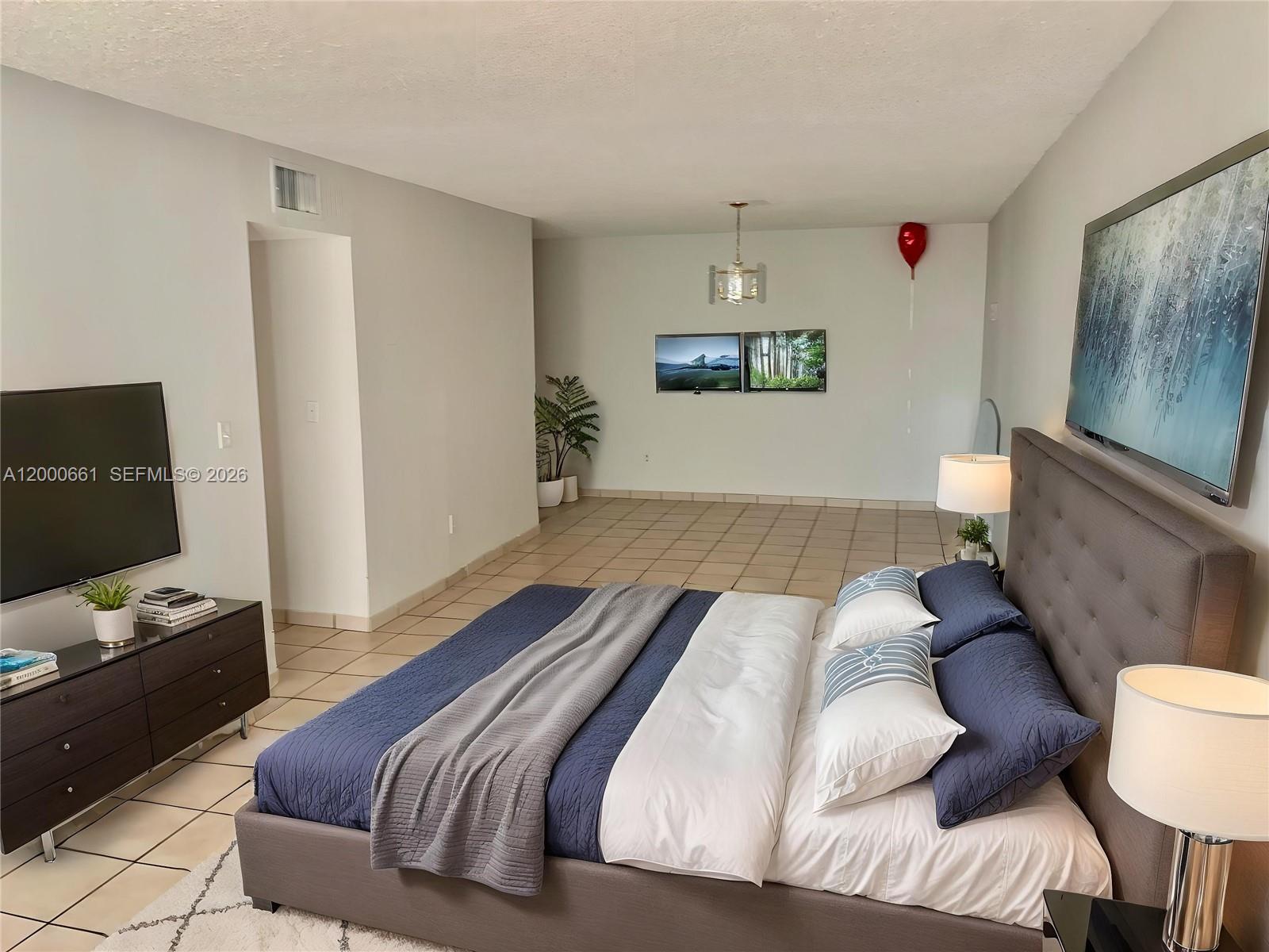 A bedroom features a large bed, tile flooring, a television, and a red balloon — 7345 W 4th Ave # 203, Hialeah FL 33014, HIALEAH, FL