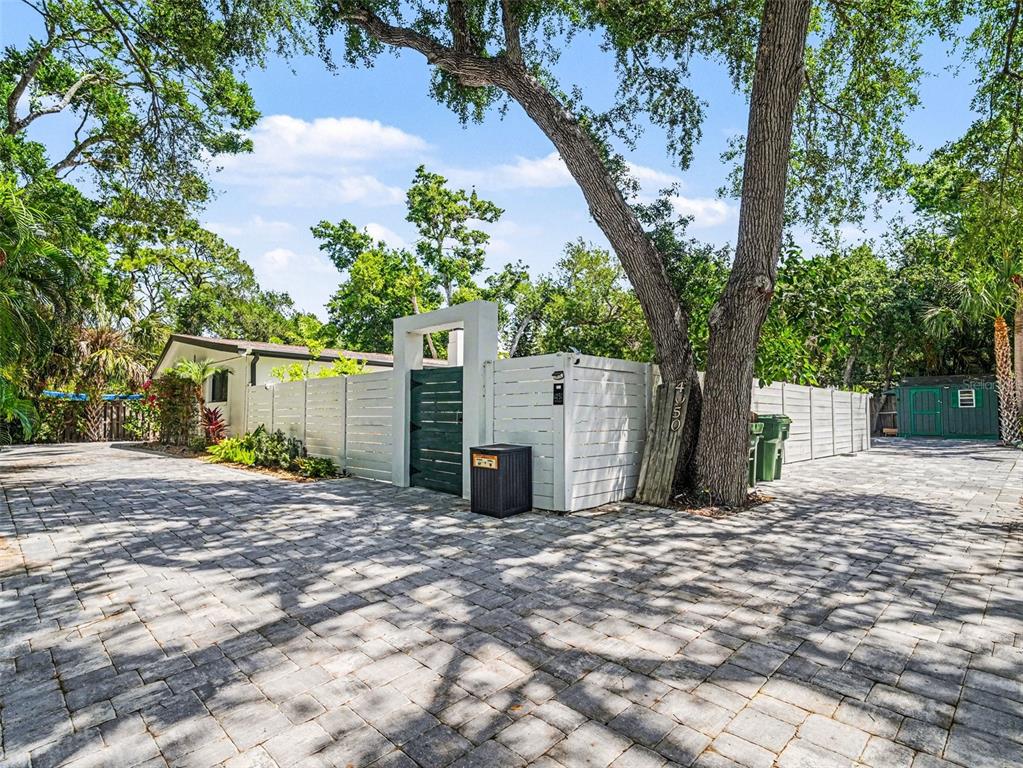 A paved backyard patio features outdoor furniture, a stone fireplace, and a small swimming pool — 4050 TURKS CAP PLACE, SARASOTA, FL