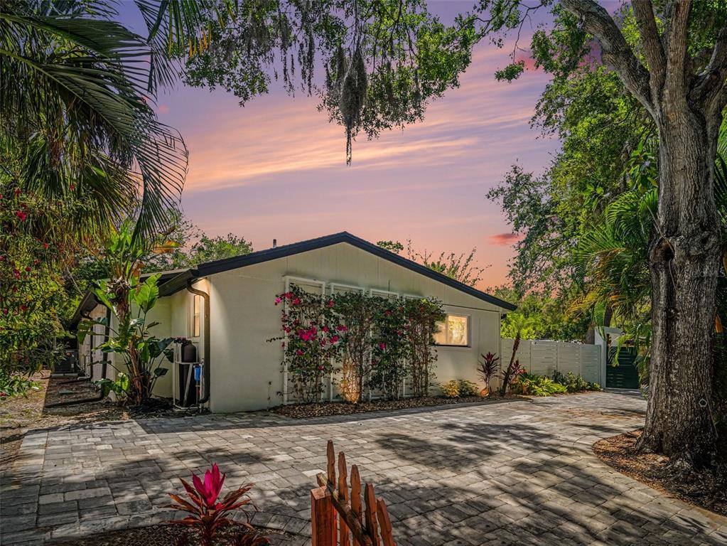 A patio features a stone fireplace, a small pool, and outdoor furniture under a sunny sky — 4050 TURKS CAP PLACE, SARASOTA, FL