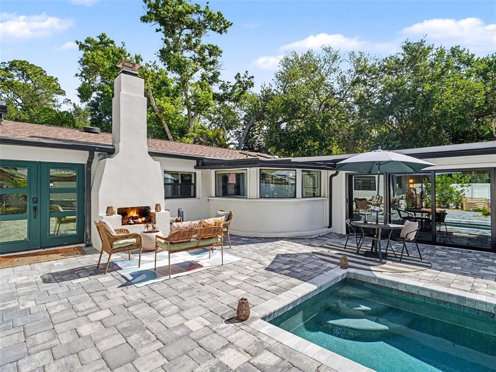 A backyard patio features a small rectangular swimming pool, stone pavers, and a built-in bench — 4050 TURKS CAP PLACE, SARASOTA, FL