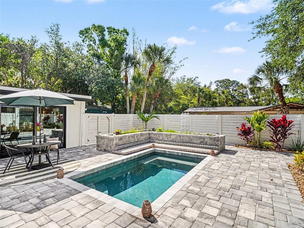 A living room features a green tiled fireplace, a patterned rug, and double glass doors — 4050 TURKS CAP PLACE, SARASOTA, FL