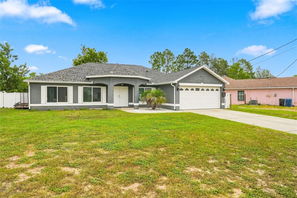 A single-story gray house with a white garage door and a large front lawn — 5341 BIRCHWOOD ROAD, SPRING HILL, FL