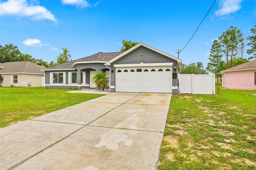 A single-story gray house with a two-car garage and a concrete driveway — 5341 BIRCHWOOD ROAD, SPRING HILL, FL