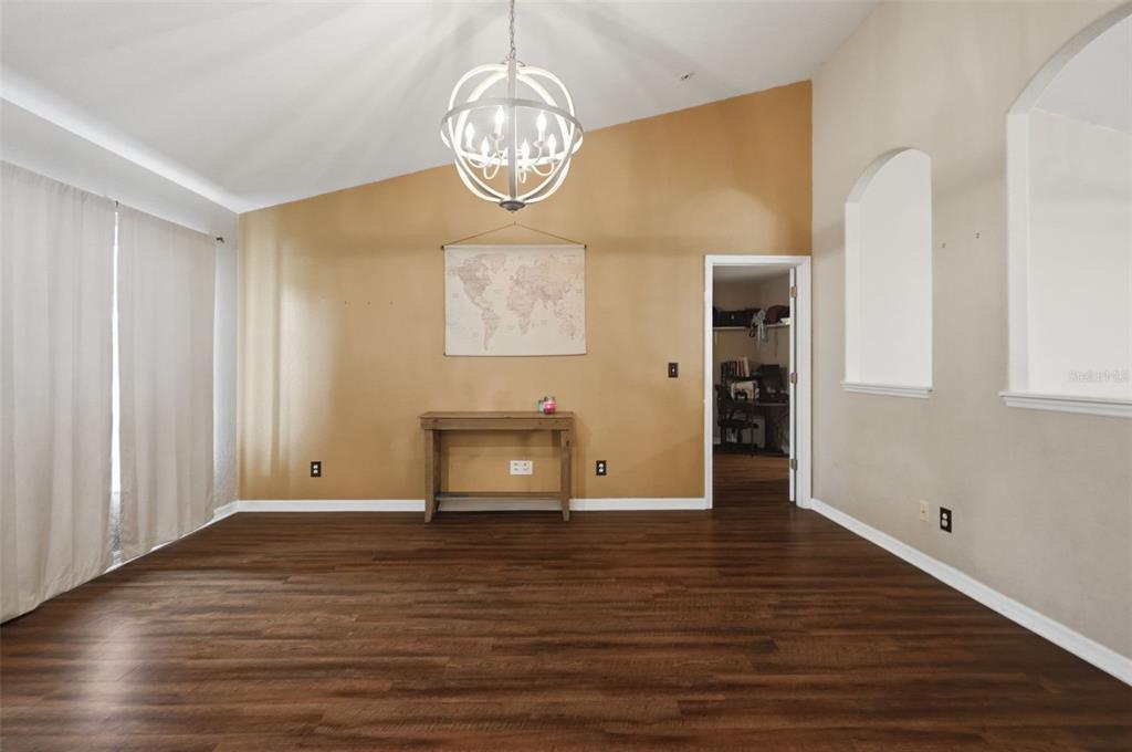 A dining room with dark wood flooring, a gold accent wall, and a globe chandelier — 5341 BIRCHWOOD ROAD, SPRING HILL, FL