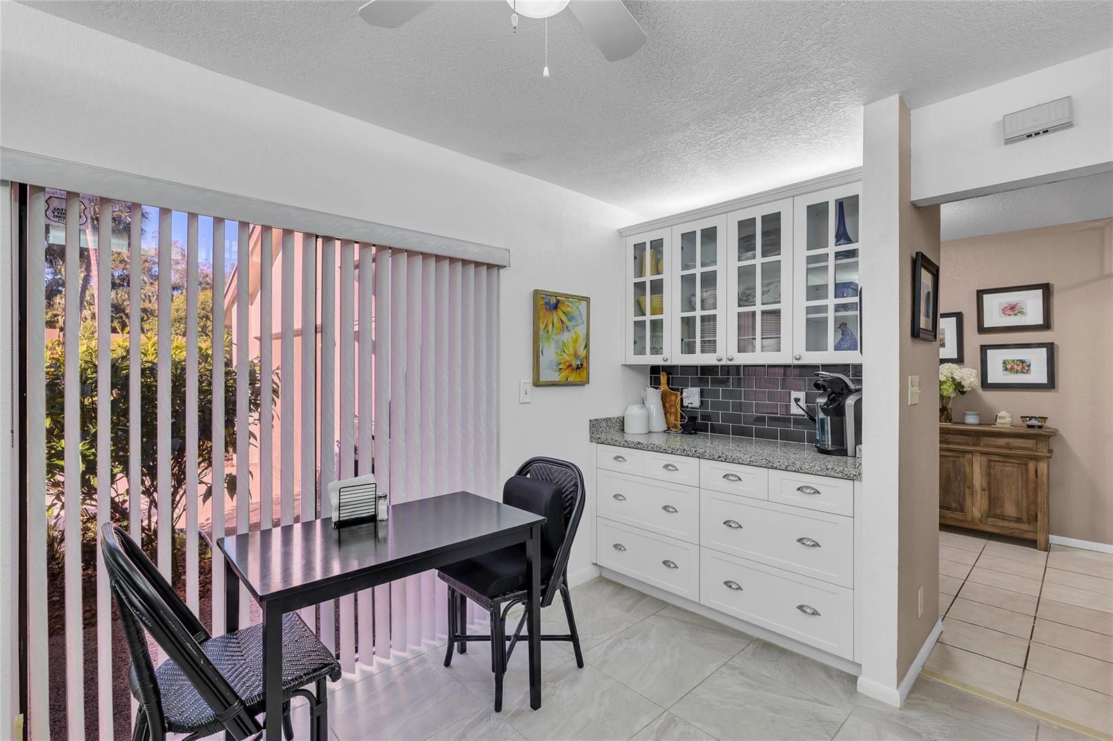 A dining area features a small black table, two chairs, and a white built-in hutch — 2260 Seagrape Circle, Coconut Creek FL 33066, COCONUT CREEK, FL