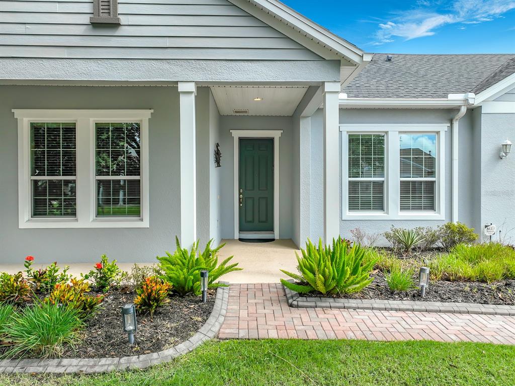 The exterior of a gray house features a green front door, white columns, and landscaping — 107 BALMY COAST ROAD, GROVELAND, FL