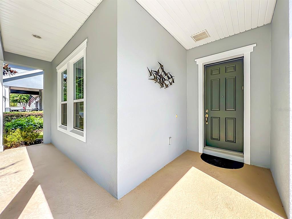 A covered front porch features a dark green door, a window, and a metal wall sculpture — 107 BALMY COAST ROAD, GROVELAND, FL