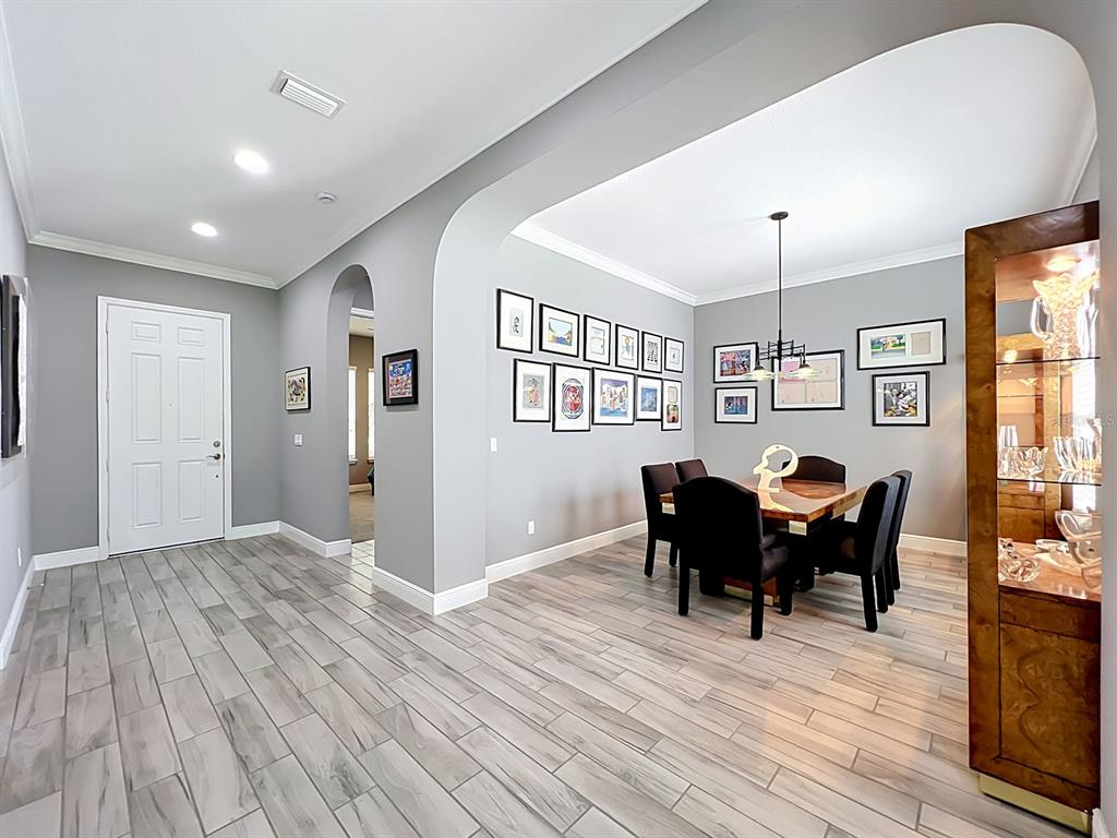 A dining room with gray walls, wood-look tile floors, and a gallery wall of framed art — 107 BALMY COAST ROAD, GROVELAND, FL