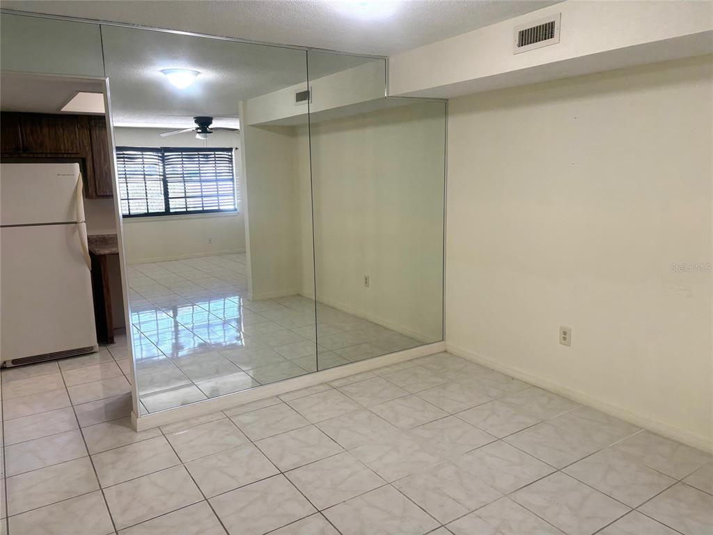 A tiled room features a large mirrored wall reflecting an adjacent kitchen and windowed area — 500 NEWELL HILL ROAD UNIT 101A, LEESBURG, FL