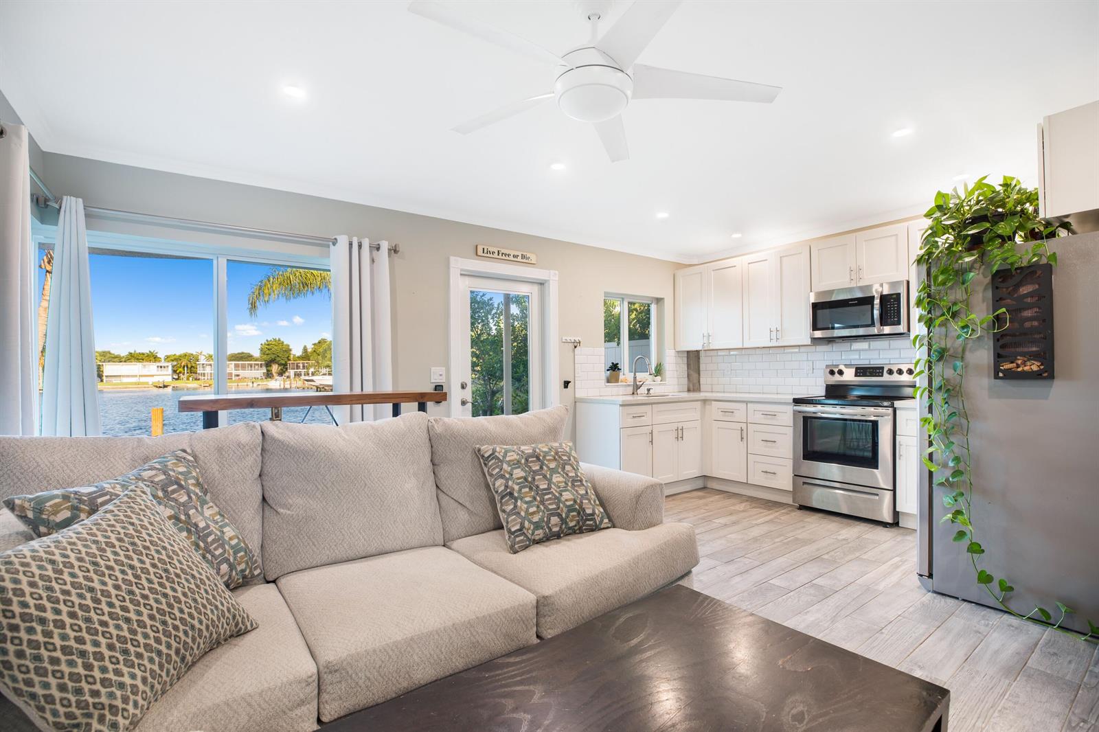 A living room with a sectional sofa flows into a kitchen with white cabinets — 1400 SE 7th Avenue # 2, Pompano Beach FL 33060, POMPANO BEACH, FL