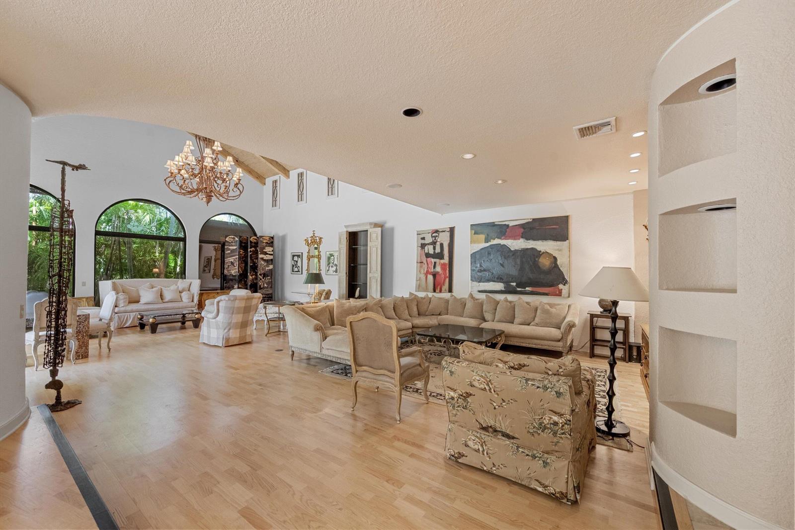 A spacious living room features light wood floors, a large sectional sofa, and arched windows — 23 Sloans Curve Drive, Palm Beach FL 33480, PALM BEACH, FL