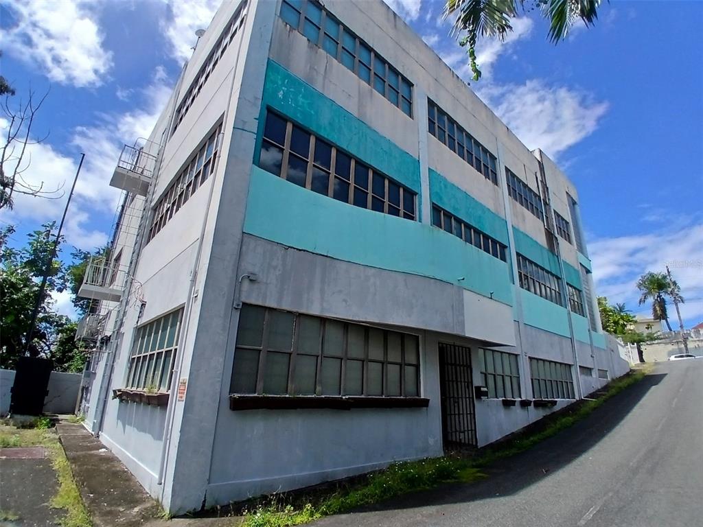 A multi-story industrial building with teal accents and large grid windows sits on a hill — 97 STATE ROAD 2 PUEBLO VIEJO, GUAYNABO, PR