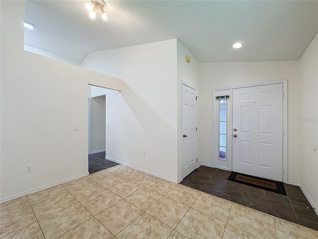 An entryway with tiled floors, a white front door, and a doorway leading to another room — 2393 PAULETTE DRIVE, HAINES CITY, FL