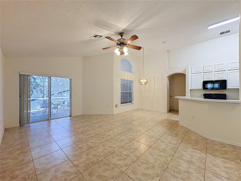 An open-concept living and dining area features tile flooring, a ceiling fan, and white cabinetry — 2393 PAULETTE DRIVE, HAINES CITY, FL
