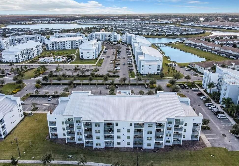 An aerial view shows several white apartment buildings surrounded by parking lots and small lakes — 4741 CLOCK TOWER DRIVE UNIT 108, KISSIMMEE, FL