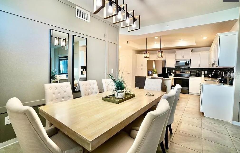 A dining room with a wooden table and upholstered chairs sits adjacent to a kitchen — 4741 CLOCK TOWER DRIVE UNIT 108, KISSIMMEE, FL