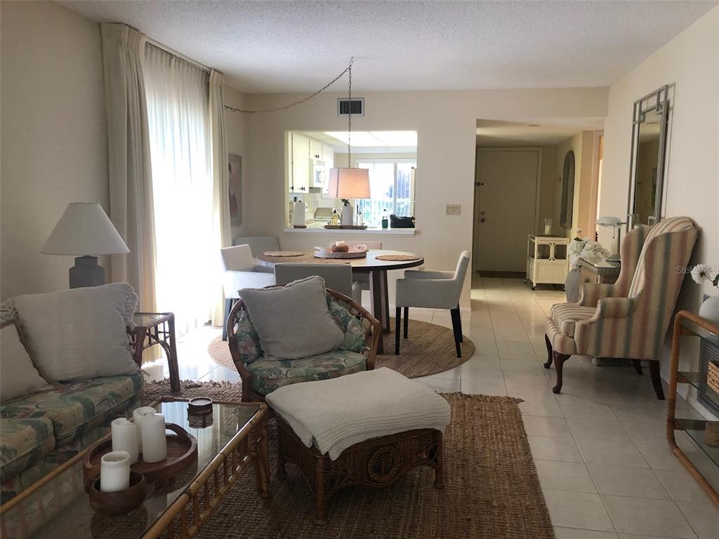 A living room and dining area with tile floors, wicker furniture, and a pass-through kitchen — 5226 MARSH FIELD LANE UNIT 11, SARASOTA, FL