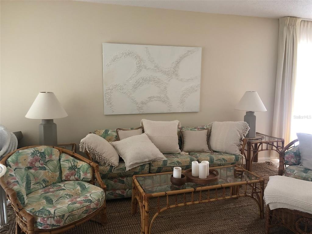 A living room features a floral sofa, rattan furniture, and textured wall art — 5226 MARSH FIELD LANE UNIT 11, SARASOTA, FL