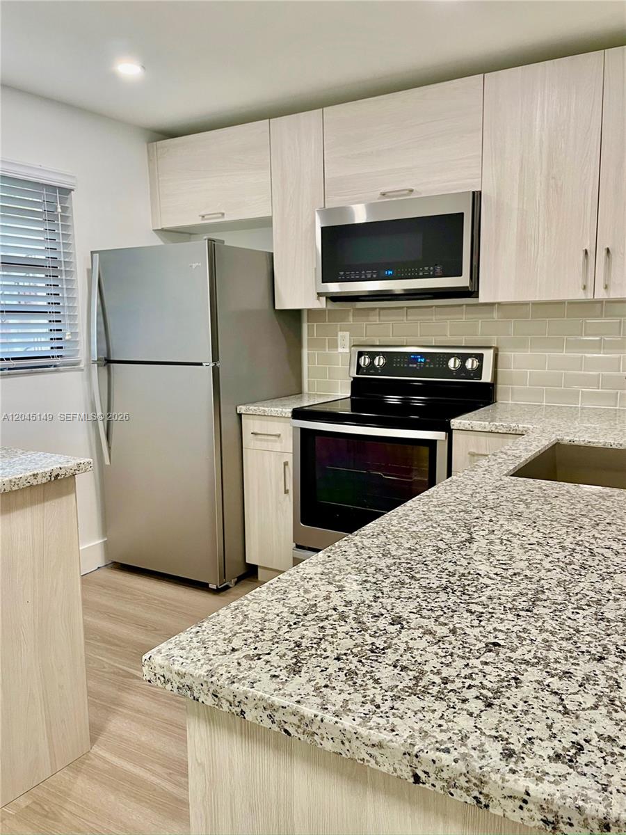 A kitchen features light wood cabinets, stainless steel appliances, and speckled granite countertops — 10835 SW 112th Ave # 212, Miami FL 33176, MIAMI, FL
