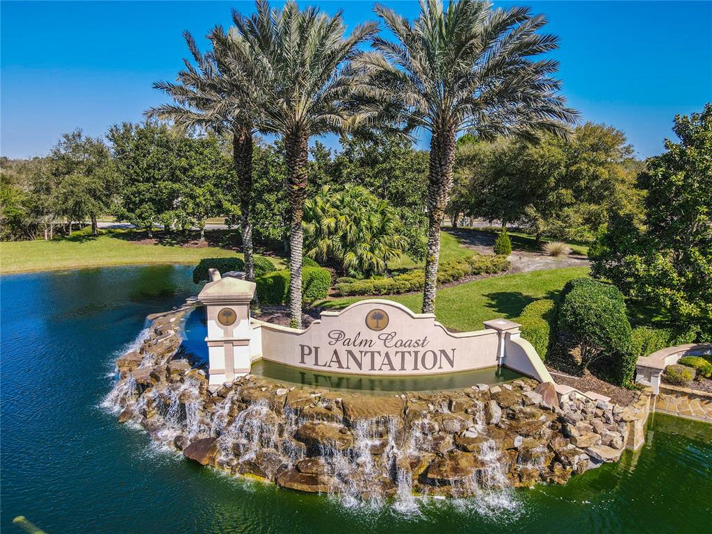 An aerial view shows a stone monument sign for Palm Coast Plantation with a waterfall feature — 22 HERON DRIVE, PALM COAST, FL