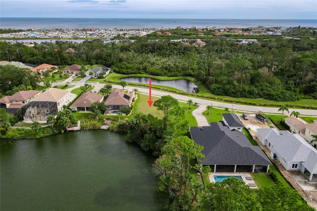 An aerial view shows a vacant residential lot situated between two houses near a lake — 22 HERON DRIVE, PALM COAST, FL