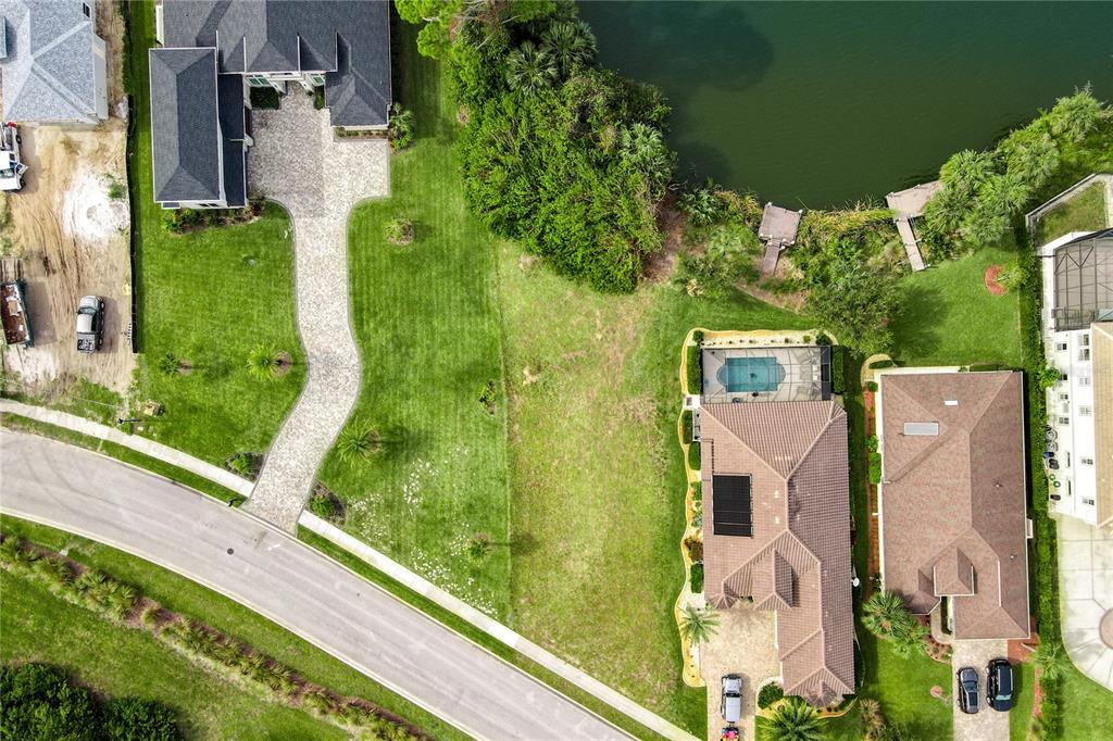 An aerial view shows two houses with paved driveways, a central grassy lot, and a lake — 22 HERON DRIVE, PALM COAST, FL
