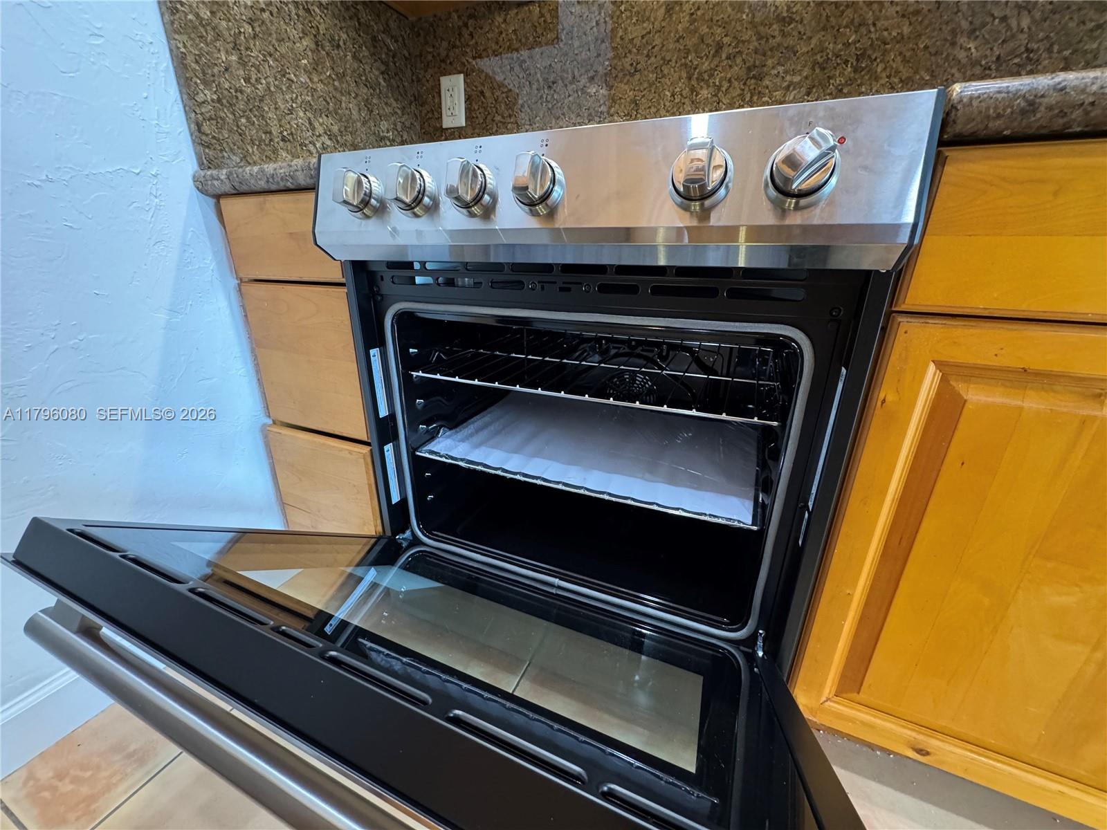 A stainless steel oven with an open door is set between wooden cabinets and countertops — 1700 Pierce St # 202, Hollywood FL 33020, HOLLYWOOD, FL