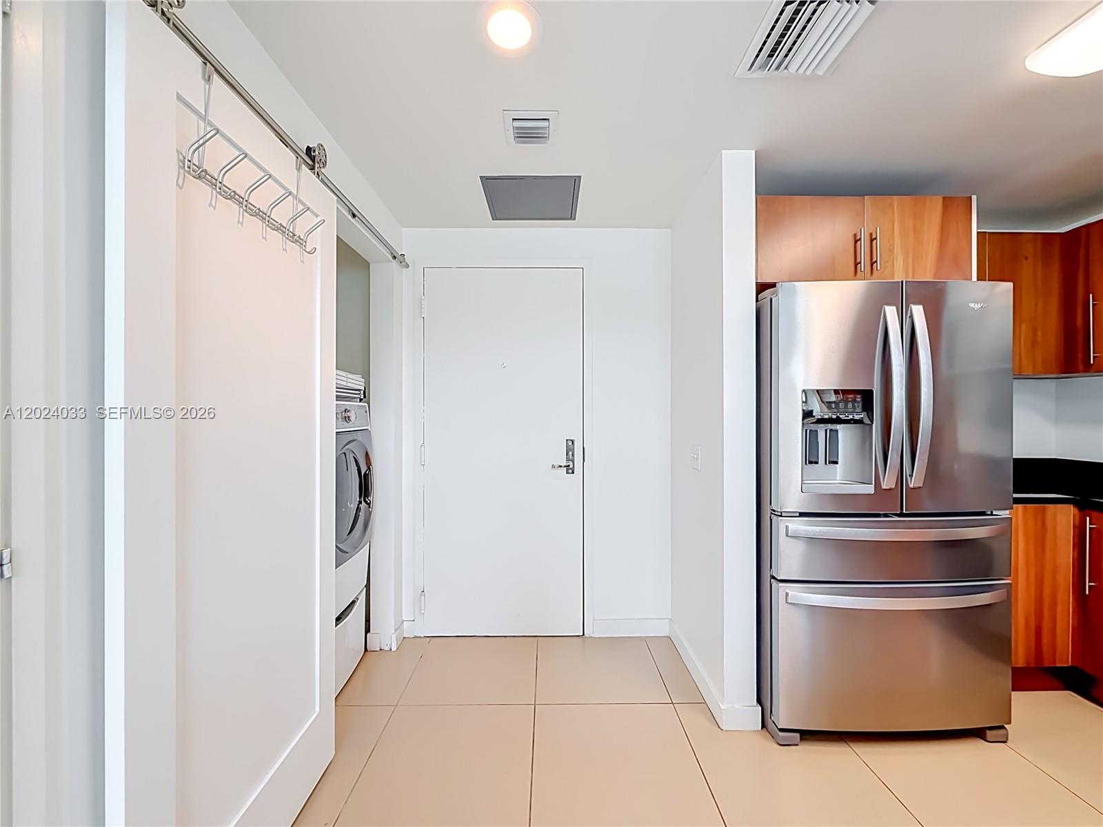 A kitchen area features a stainless steel refrigerator, light tile flooring, and a laundry closet — 300 S Biscayne Blvd # 1016, Miami FL 33131, MIAMI, FL