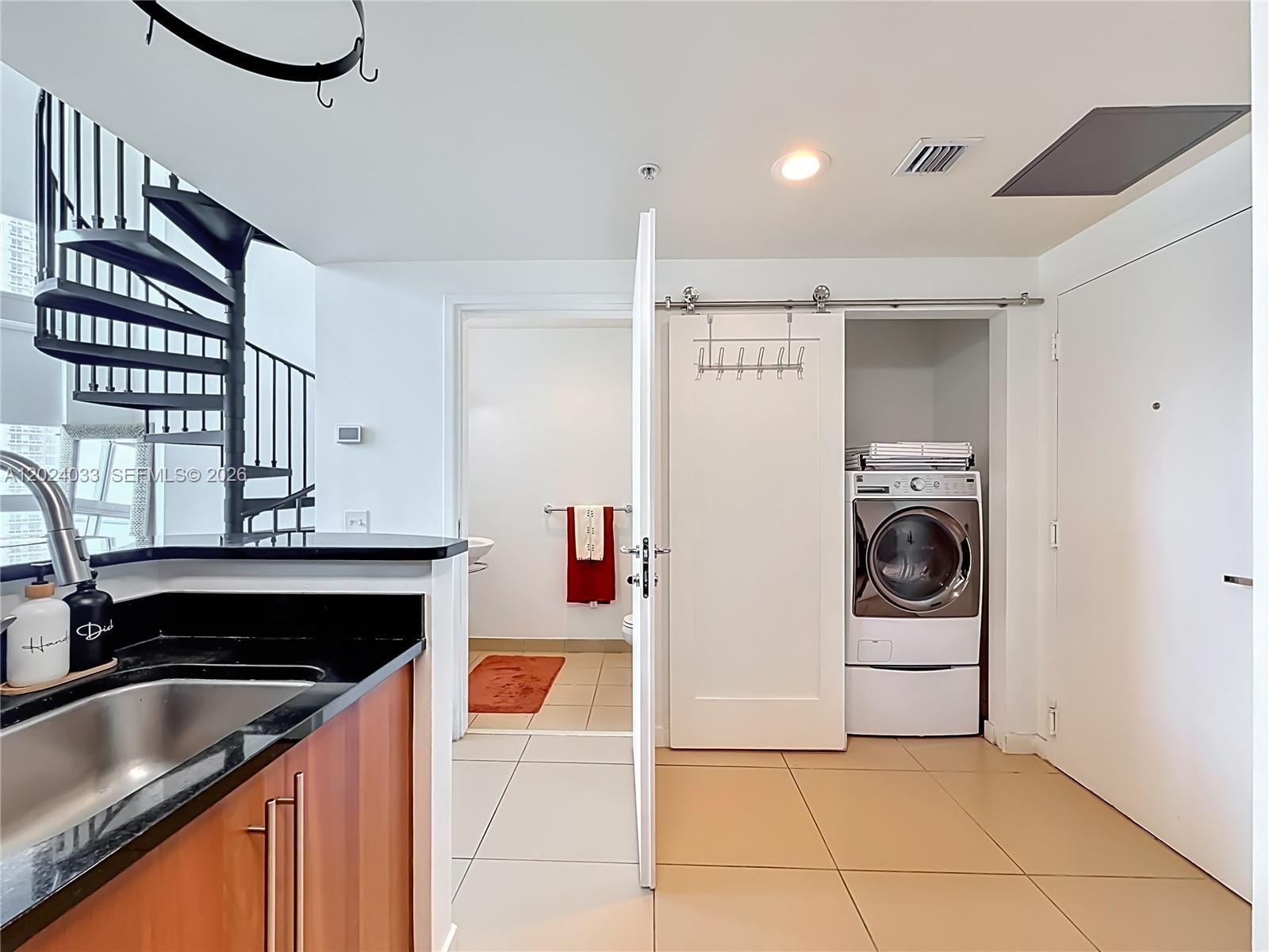 A kitchen area features a spiral staircase, a laundry closet with a sliding door, and tile flooring — 300 S Biscayne Blvd # 1016, Miami FL 33131, MIAMI, FL