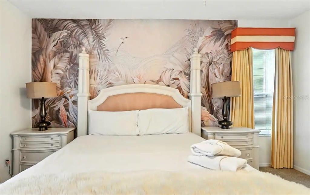 A bedroom features a four-poster bed against a tropical-themed mural wall with matching nightstands — 8520 SUNRISE KEY DRIVE, KISSIMMEE, FL
