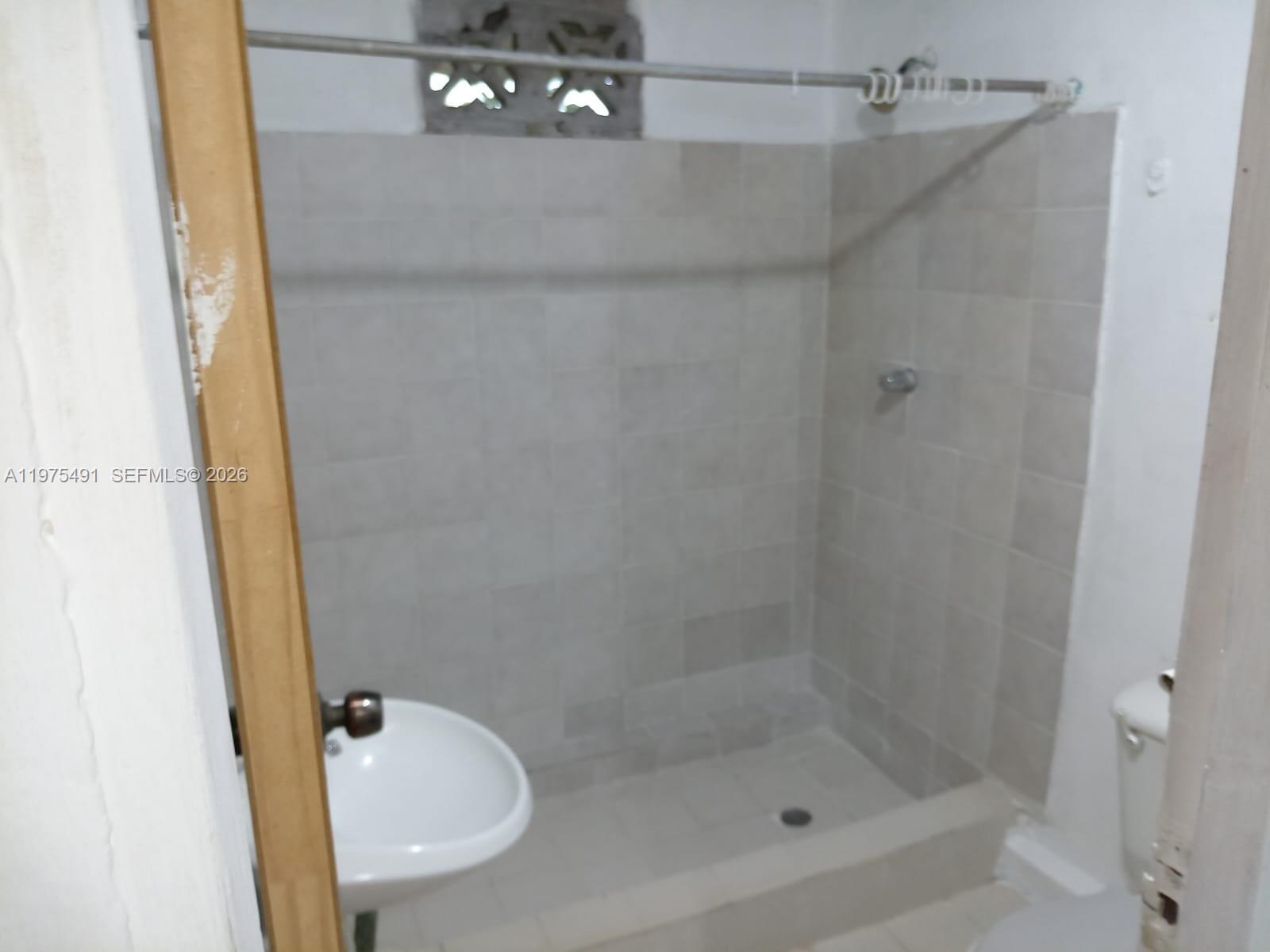 A small bathroom features a tiled walk-in shower, a wall-mounted sink, and a toilet — 4150 SANTA CLARA, ou N/A, ou