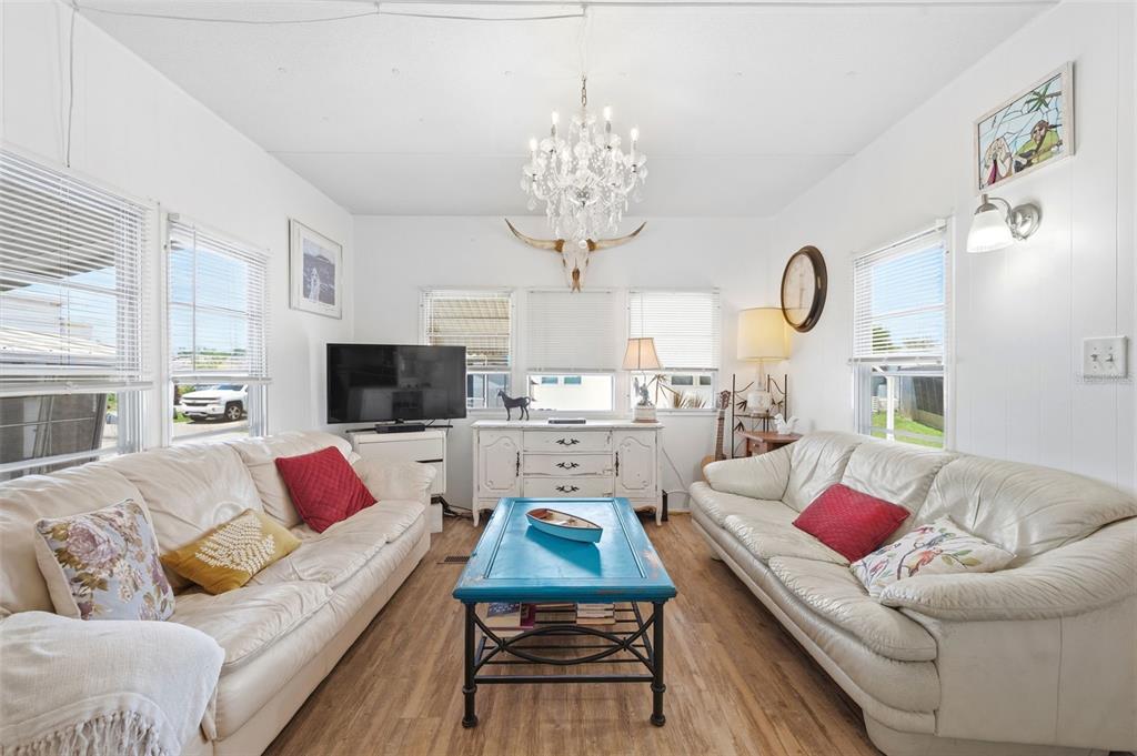 A living room features two white leather sofas, a blue coffee table, and a chandelier — 4687 67TH STREET N UNIT 23, ST PETERSBURG, FL