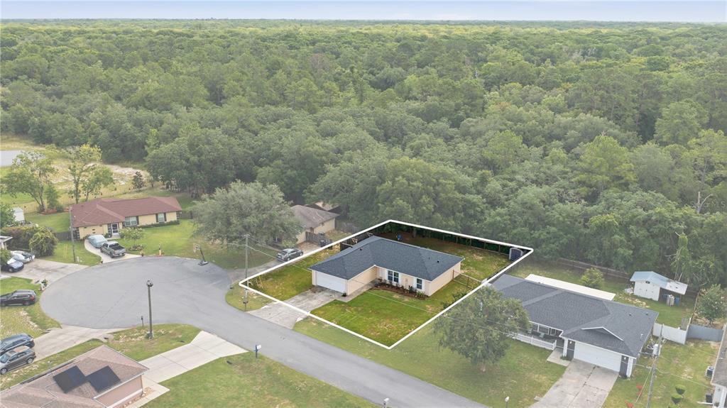 An aerial view shows a single-story house with a fenced backyard surrounded by dense trees — 5 FIR DRIVE, OCALA, FL