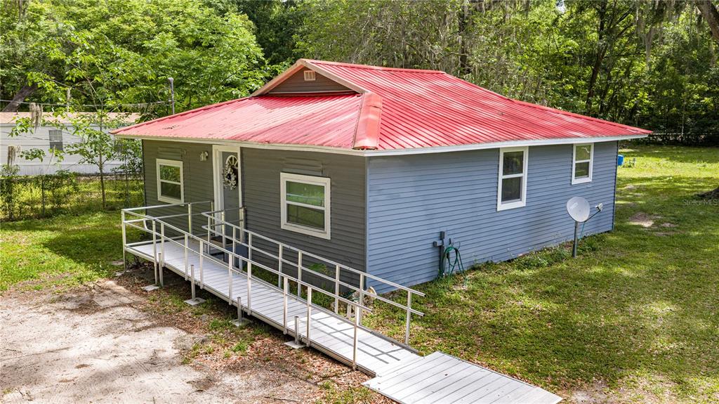 A gray house with a red metal roof features a long metal wheelchair ramp — 3331 SE 11TH AVENUE, OCALA, FL