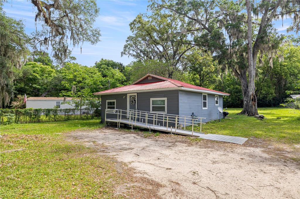 A gray house with a red metal roof and a wheelchair ramp in a yard — 3331 SE 11TH AVENUE, OCALA, FL