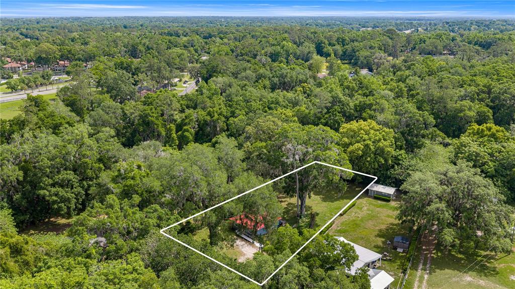 An aerial view shows a house with a red roof situated on a wooded lot — 3331 SE 11TH AVENUE, OCALA, FL