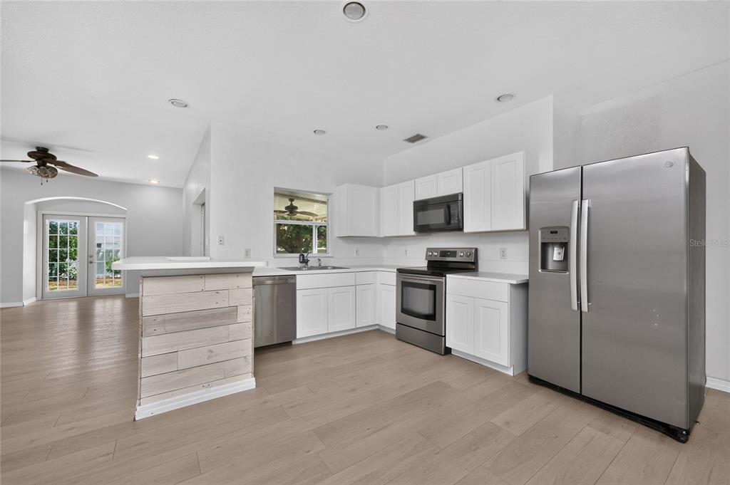 A kitchen with white cabinets, stainless steel appliances, and a wood-paneled breakfast bar — 11082 VANESSA AVENUE, ENGLEWOOD, FL