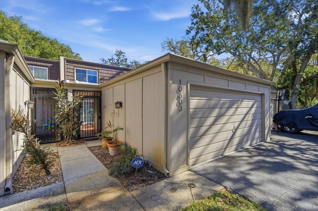 A tan exterior of a house features a garage, a gated entryway, and a concrete walkway — 10603 CARROLLBROOK WAY UNIT 10603, TAMPA, FL