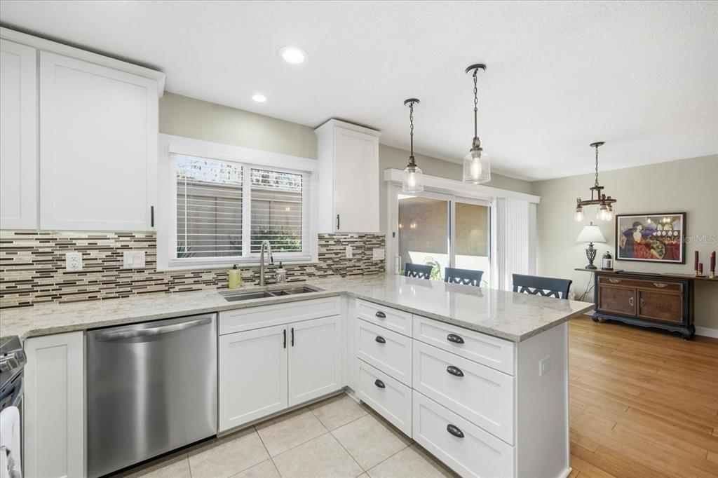 A kitchen with white cabinets, stainless steel appliances, a tiled backsplash, and a peninsula island — 10603 CARROLLBROOK WAY UNIT 10603, TAMPA, FL