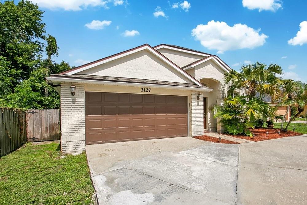 A single-story house with a two-car garage, white brick accents, and a palm tree — 3127 BIRMINGHAM BOULEVARD, ORLANDO, FL