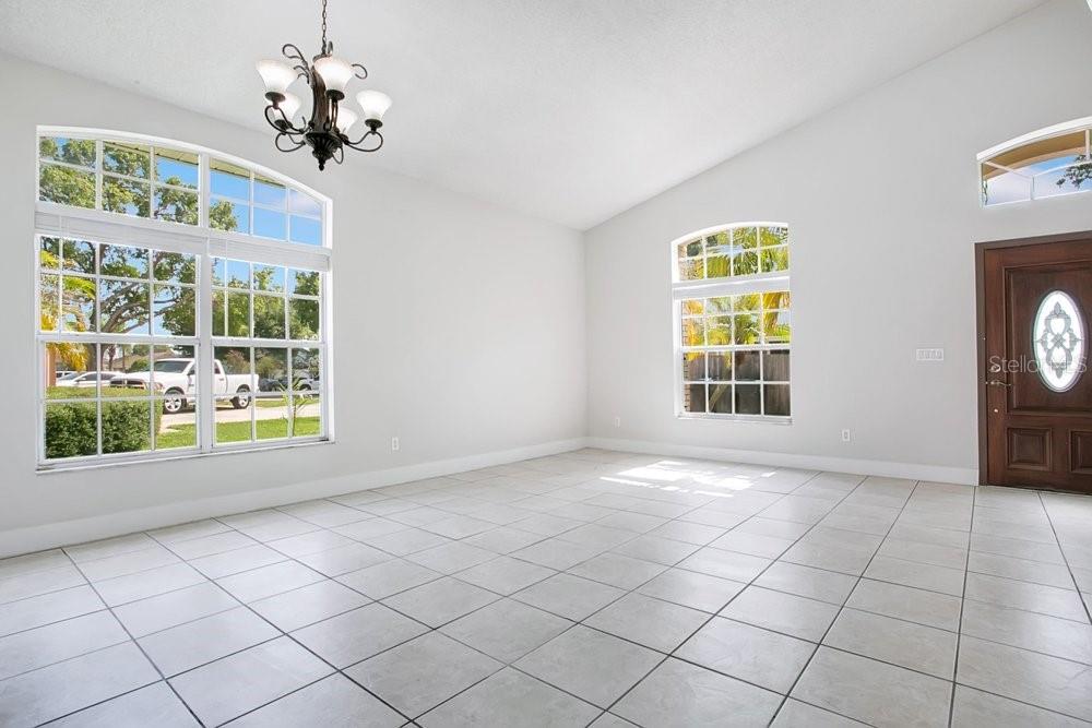 An empty room with white walls, tile flooring, a chandelier, and large arched windows — 3127 BIRMINGHAM BOULEVARD, ORLANDO, FL
