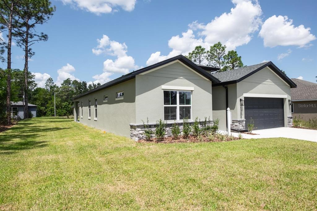 A single-story house with light green stucco, stone accents, and a dark garage door — 2424 SW 159 LANE, OCALA, FL