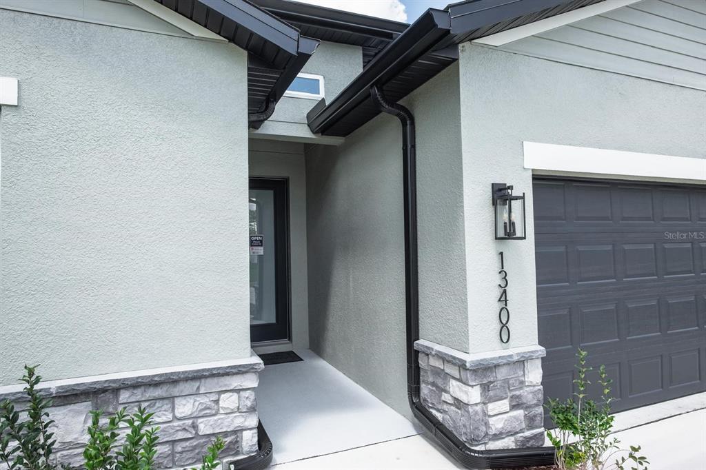 The exterior of a house features a stone-accented facade, a dark garage door, and a recessed entryway — 2424 SW 159 LANE, OCALA, FL