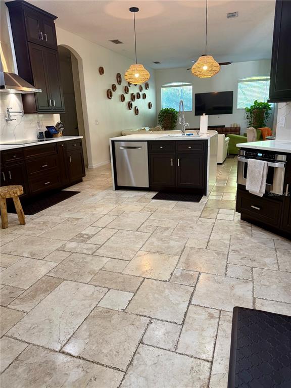 A kitchen features dark wood cabinetry, a central island with a sink, and stone flooring — 1584 SHADOWMOSS CIRCLE, LAKE MARY, FL